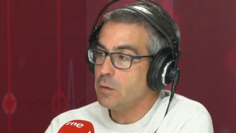 Hombre con gafas y auriculares en un estudio de radio, mirando concentrado hacia un lateral junto a un micrófono.