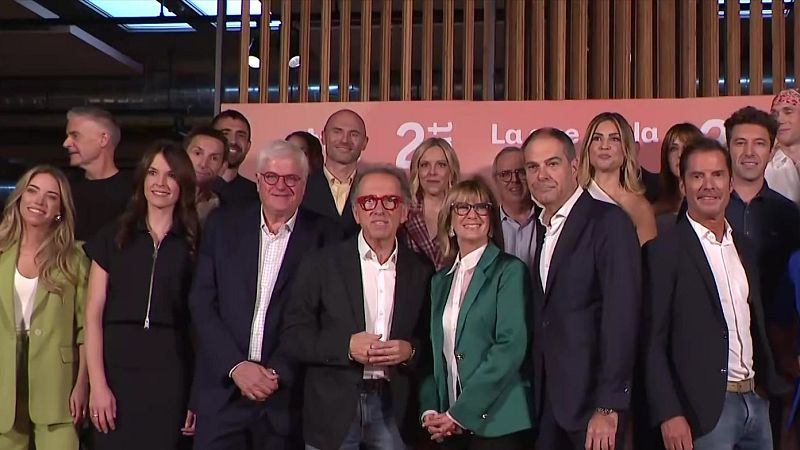 Un grupo de profesionales de la televisión posa sonriente frente a un panel promocional con Jordi Hurtado y Gemma Nierga en el centro.