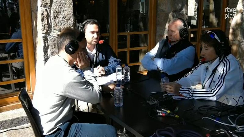 Cuatro personas con auriculares y micrófonos participan en un programa radiofónico al aire libre alrededor de una mesa con material técnico.