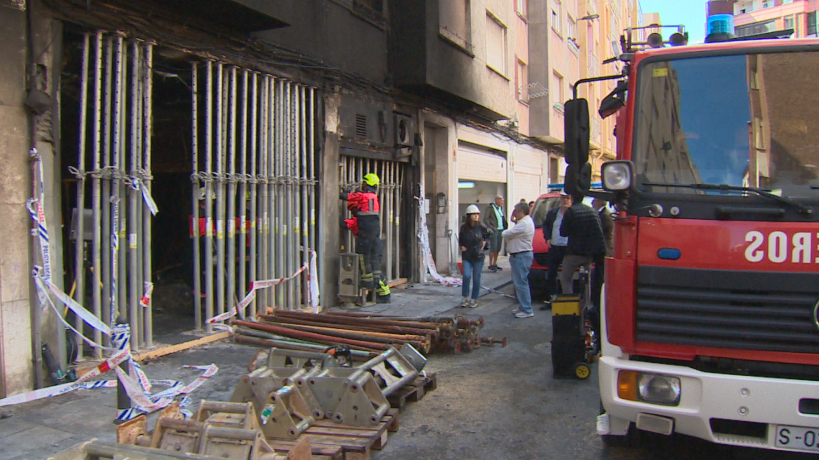 Bomberos de Santander apuntalan con puntales metálicos un edificio afectado por un incendio en una calle urbana.