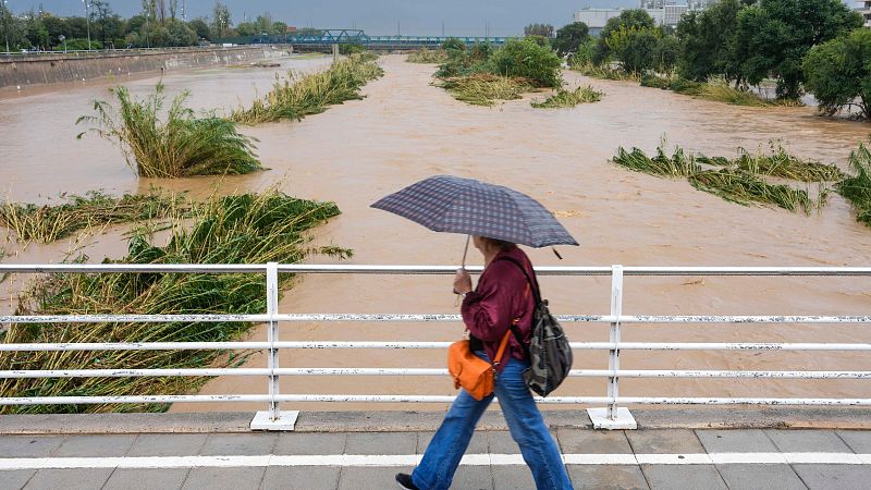 Una mujer pasea ante la crecida del río