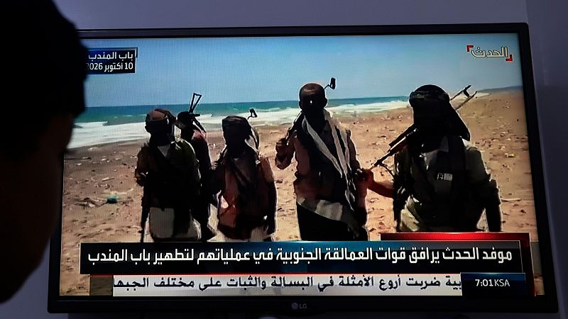 Una persona observa una transmisión televisiva que muestra a tropas yemeníes respaldadas por Arabia Saudí
