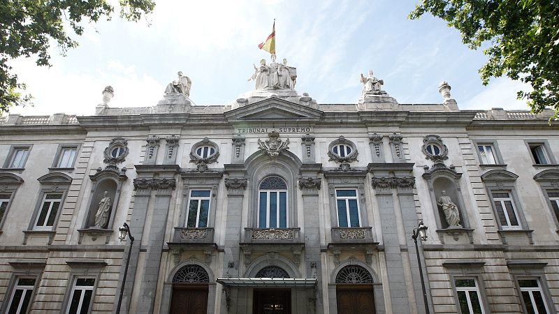 Fachada clásica del Tribunal Supremo de España en Madrid, con relieves, esculturas, grandes ventanales y la bandera nacional ondeando.