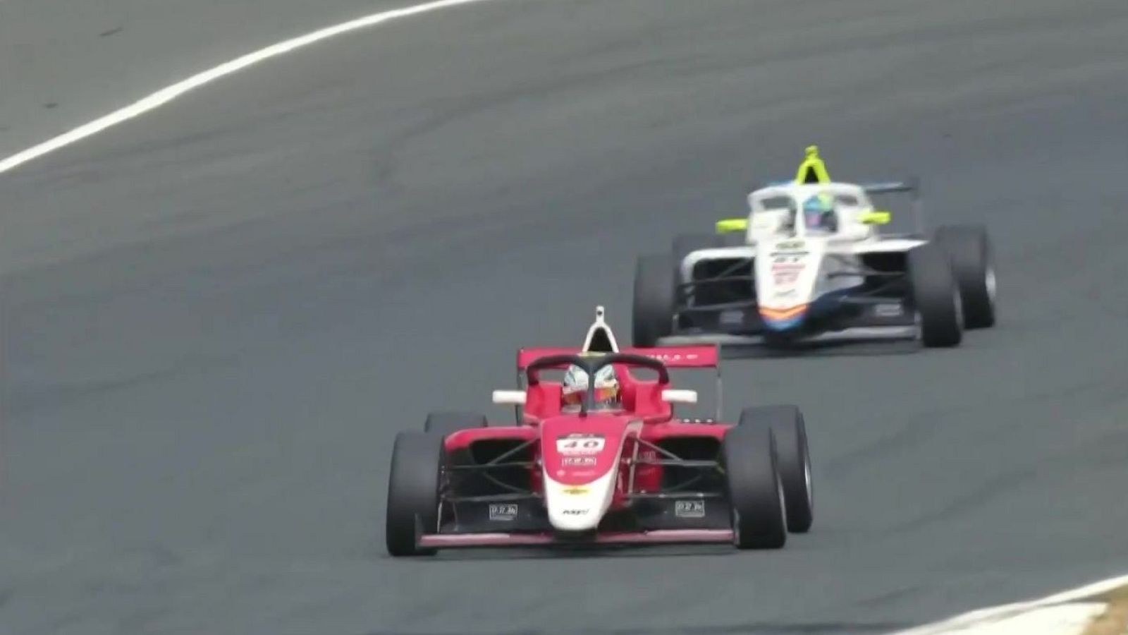 Dos monoplazas de carreras circulan en circuito cerrado, uno rojo con el número 40 y otro blanco con detalles amarillos.