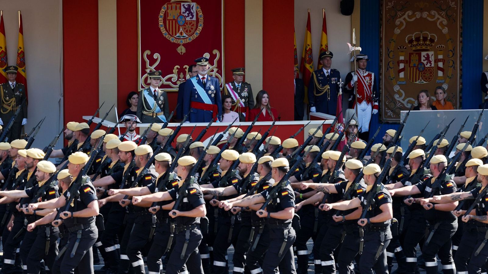 Desfile de la Unidad Militar de Emergencias con uniforme negro y boina mostaza ante la tribuna real presidida por los reyes y la princesa Leonor.