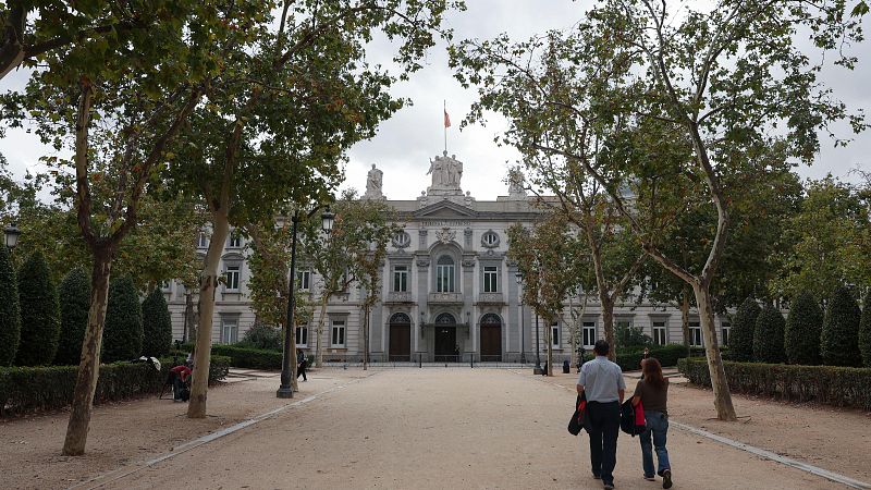 Fachada principal del Tribunal Supremo de España en Madrid, con un paseo arbolado y equipos de prensa en primer plano.