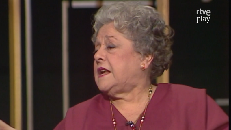 Plano medio corto de la actriz española Rafaela Aparicio hablando con expresividad en un plató con el logotipo de rtve play en la esquina superior derecha.