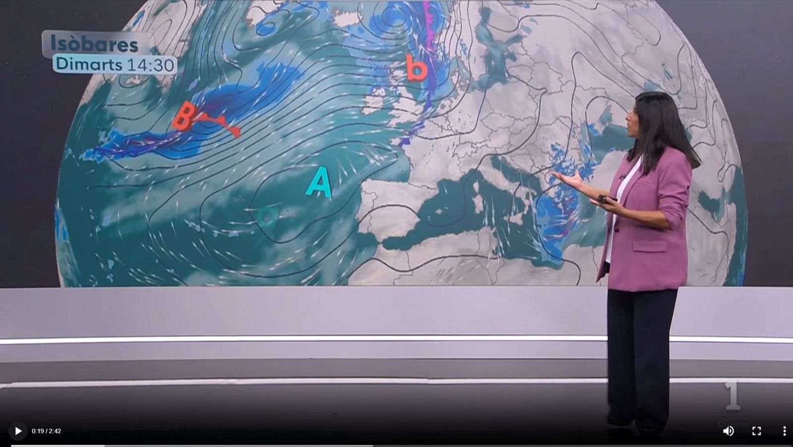 Una presentadora señala un mapa de isobaras en una gran pantalla de plató, explicando la previsión meteorológica frente a un gráfico del Atlántico y Europa.