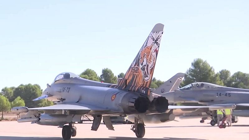 Dos cazas Eurofighter Typhoon en una base militar, destacando un avión con decoración especial de tigre en la cola y personal de mantenimiento en tierra.