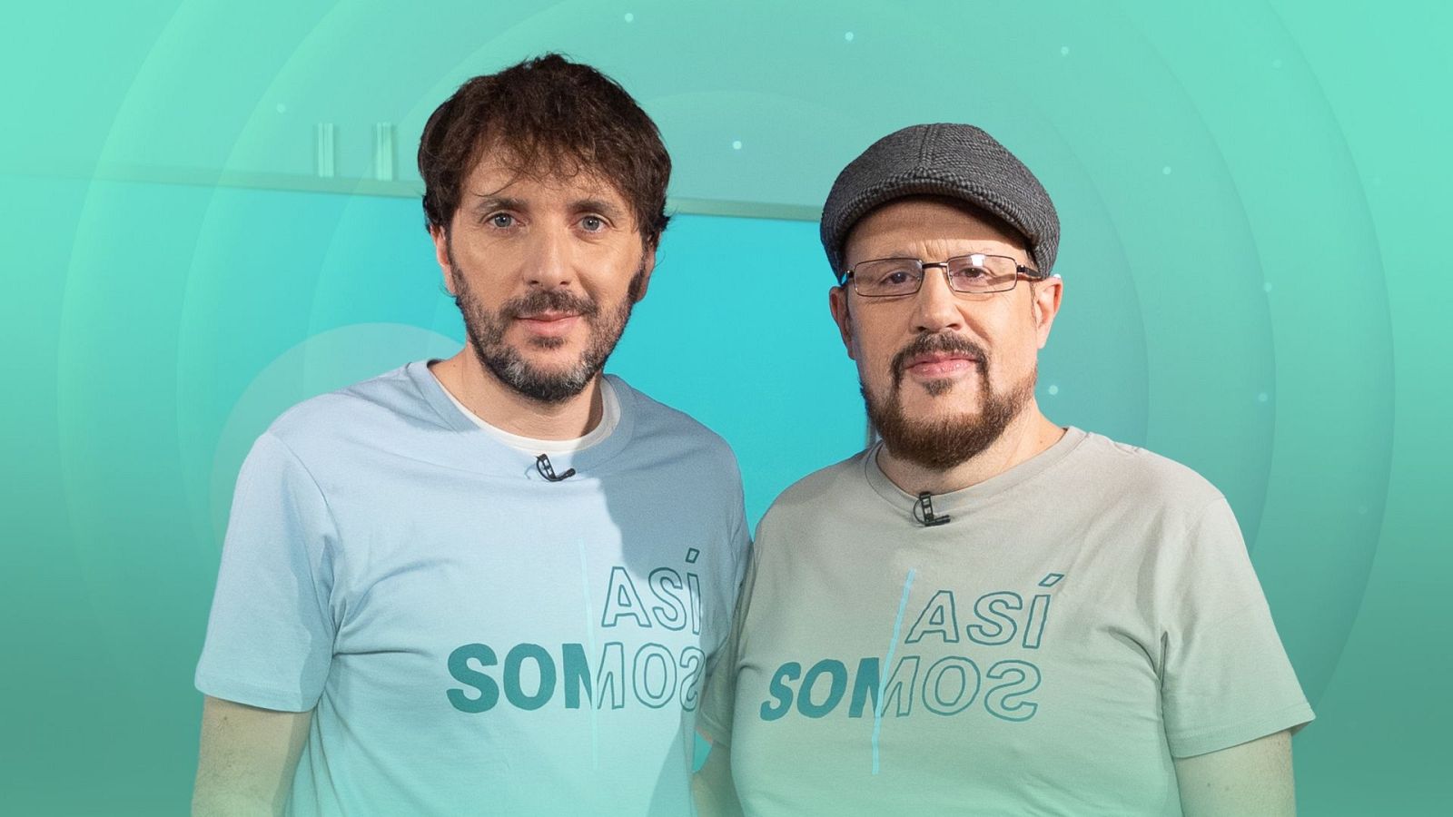 Dos hombres con camisetas informales y micrófonos de solapa posan ante un fondo gráfico digital en tonos turquesa.