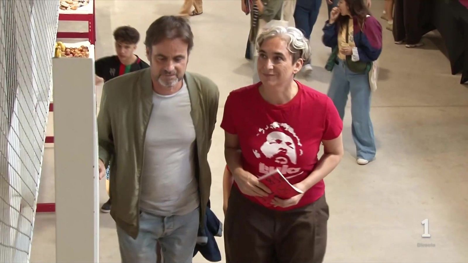 La política Ada Colau camina en un espacio industrial luciendo una camiseta roja con la imagen de Lula da Silva.