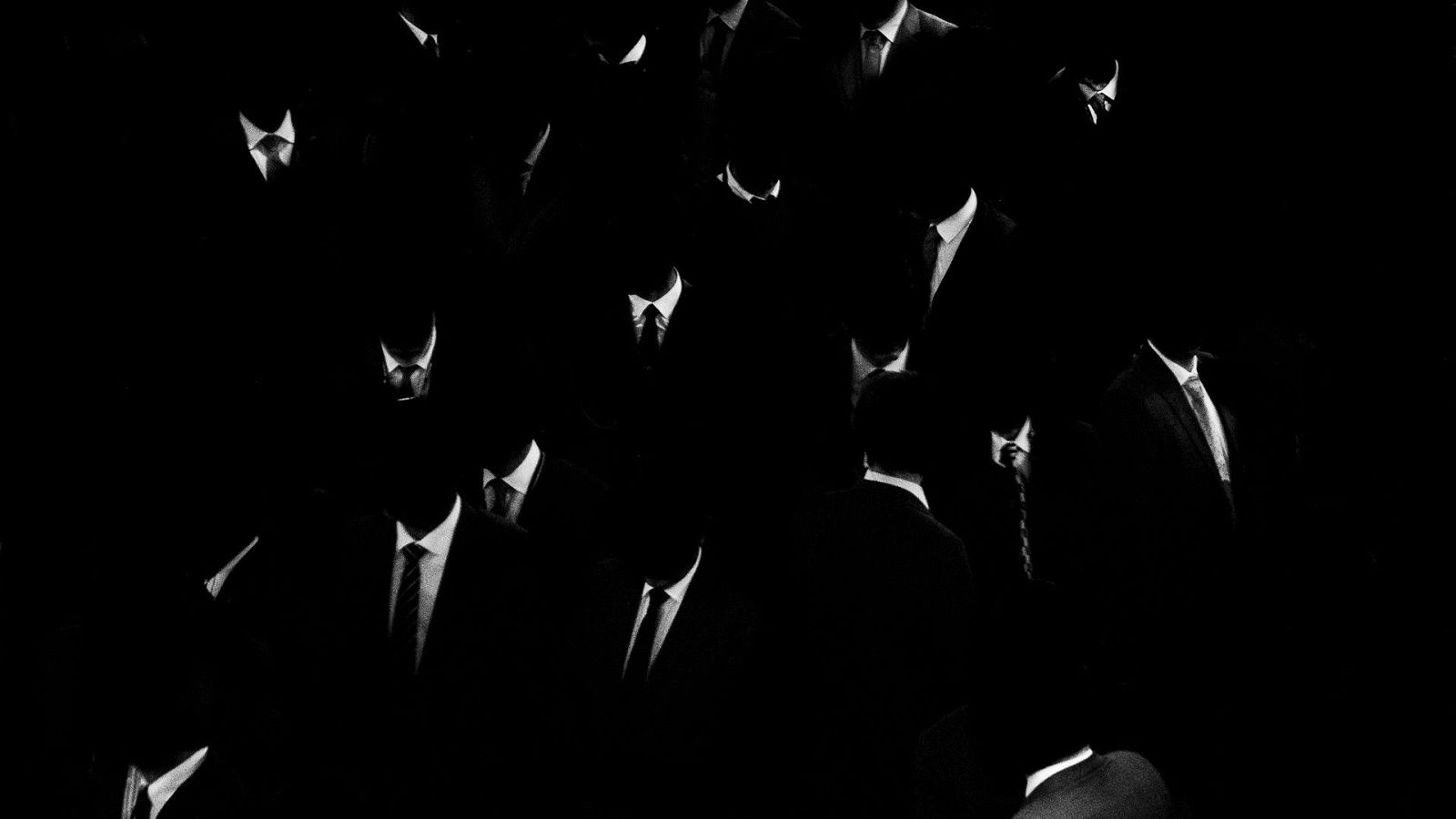 Siluetas de hombres con traje formal y rostros en sombra sobre fondo negro, destacando camisas blancas y corbatas en claroscuro.