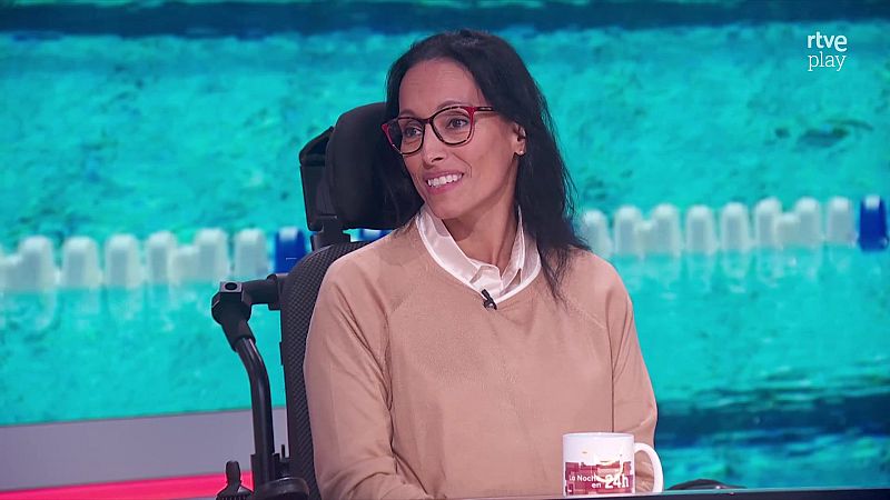 La nadadora Teresa Perales sonr�e sentada en su silla de ruedas durante una entrevista en un plat� de televisi�n con una taza corporativa sobre la mesa.