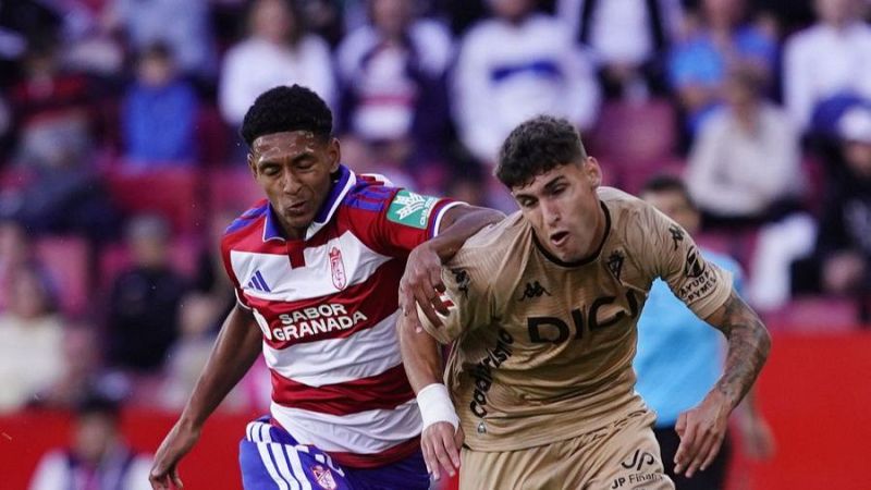 Dos futbolistas disputan intensamente la posici�n en un partido, mostrando gran esfuerzo f�sico y tensi�n corporal.
