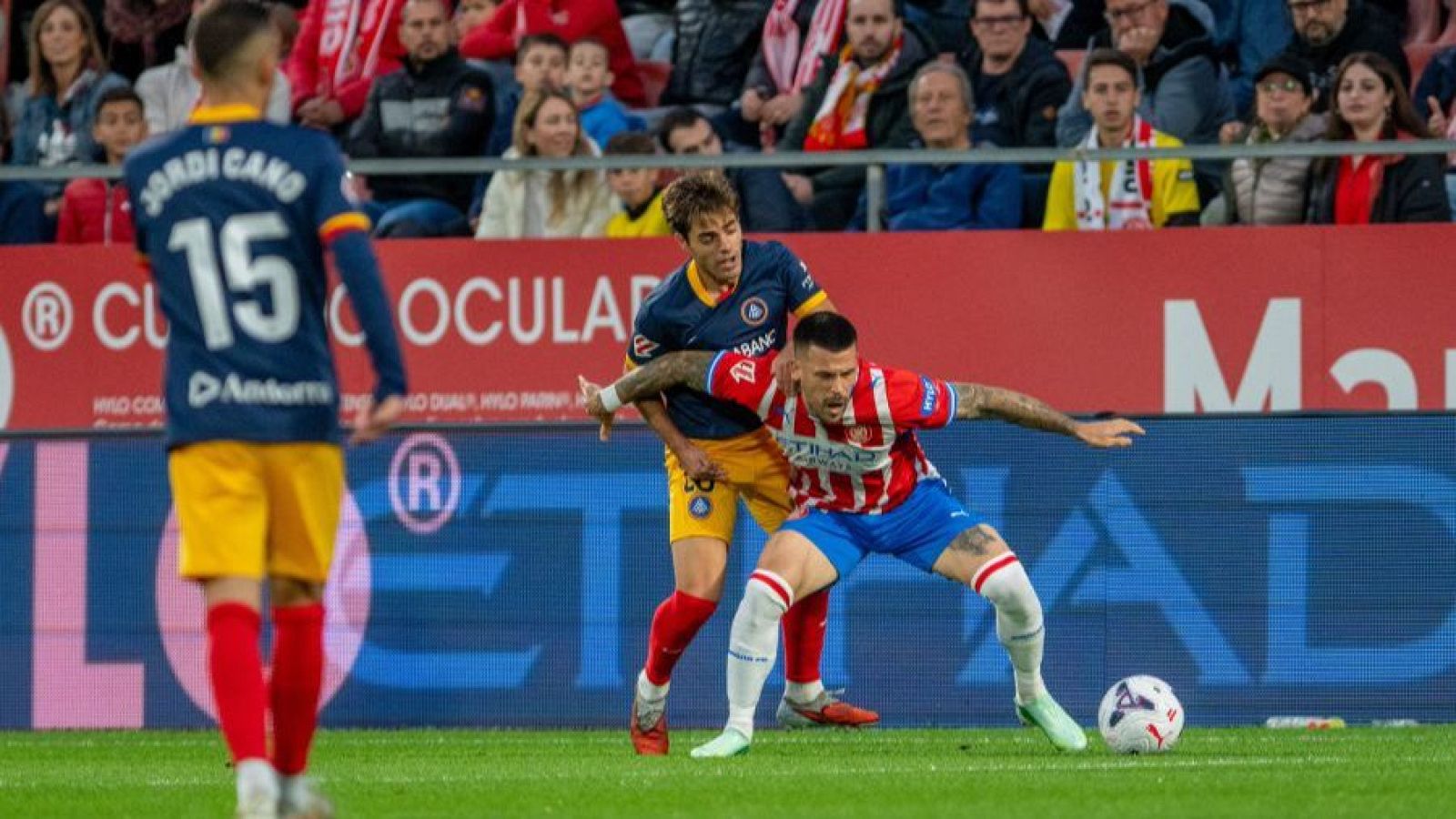 David López, del Girona FC, protege el balón ante la presión de un jugador del FC Andorra durante un partido de fútbol.