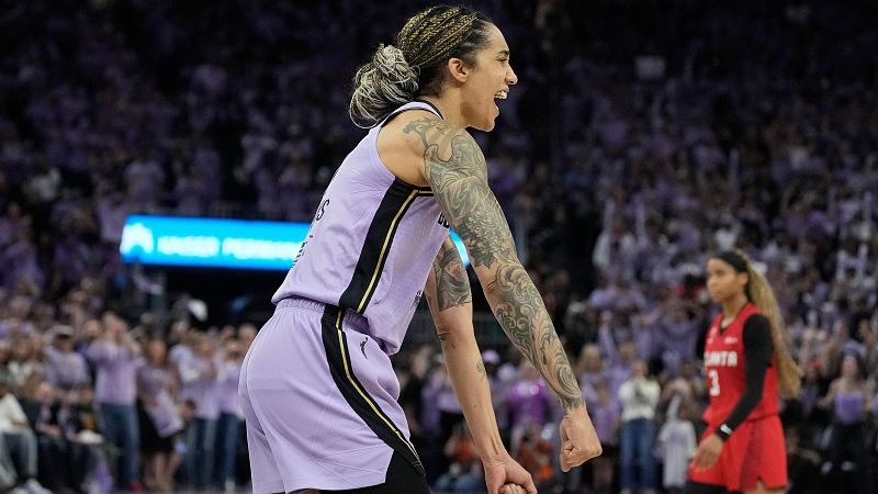 La jugadora Brittney Griner celebra eufórica con la equipación violeta de Phoenix Mercury en un partido de baloncesto profesional con la grada al fondo.