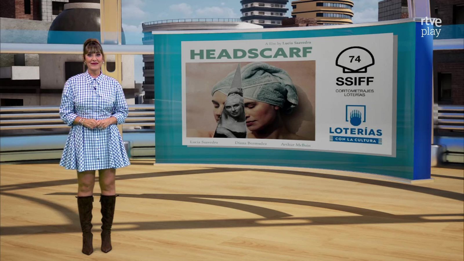 Sandra Daviú presenta un espacio informativo en un plató con una gran pantalla que muestra el cartel del cortometraje Headscarf y el logotipo de Loterías con la Cultura.