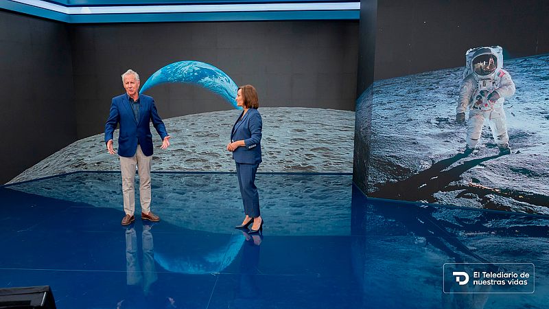 Plató de informativos con suelo azul reflectante y pantallas gigantes que muestran la superficie lunar y un astronauta.