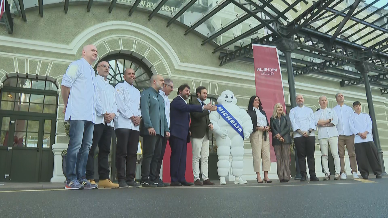 Grupo de chefs y representantes posando junto a la mascota de la Guía Michelin frente a la histórica estación de Canfranc.