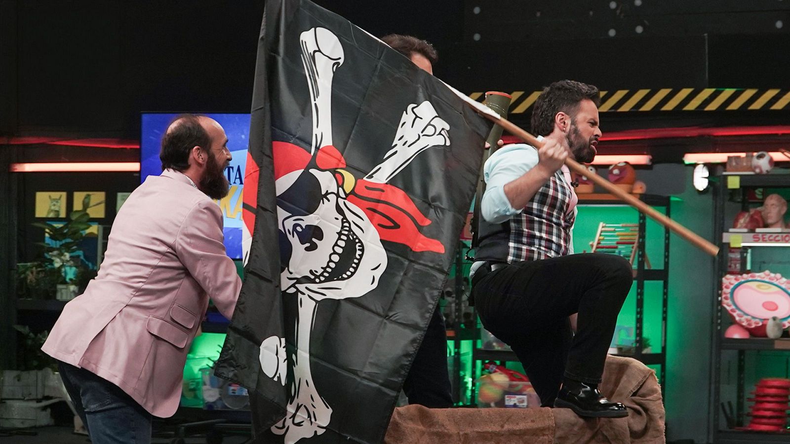 El presentador Eduardo Sáenz de Cabezón y el biólogo Ricardo Moure participan en una divertida escena de temática pirata en un plató de televisión con luces LED y atrezo científico.