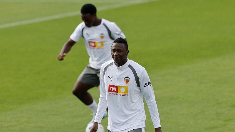 El defensa Mouctar Diakhaby camina de frente con sudadera blanca de entrenamiento, mientras Thierry Correia conduce un balón al fondo sobre césped natural.