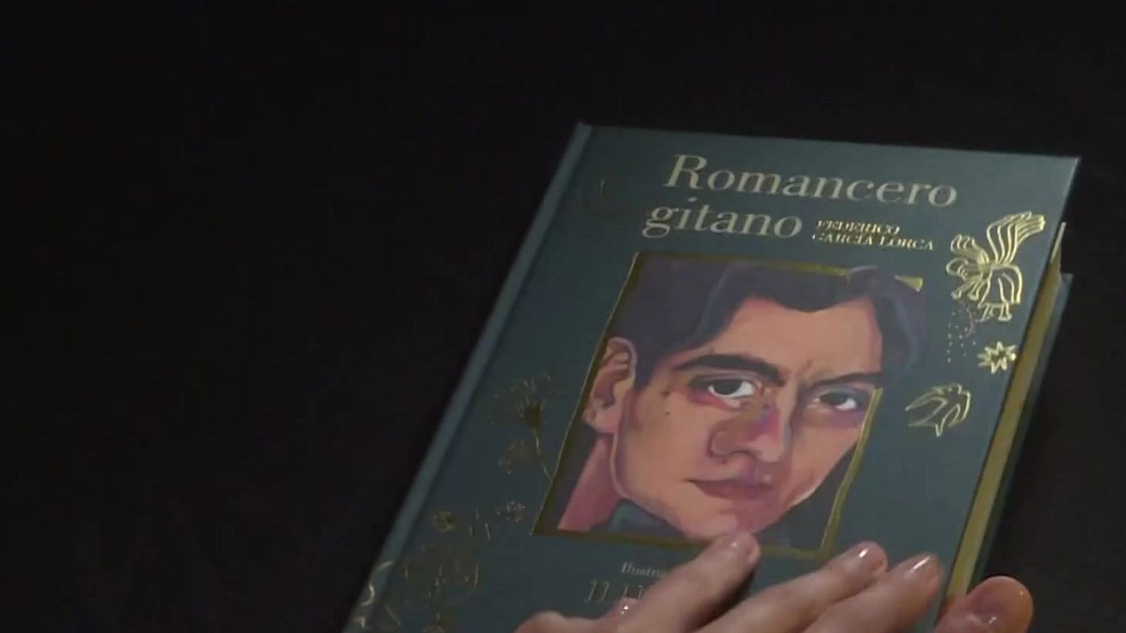 Plano detalle de la portada de una edición ilustrada del libro Romancero gitano de Federico García Lorca, sostenida con delicadeza por una mano.