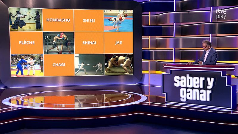 Plató de televisión con el presentador Jordi Hurtado y una gran pantalla que muestra un panel de juego sobre artes marciales y deportes de combate.