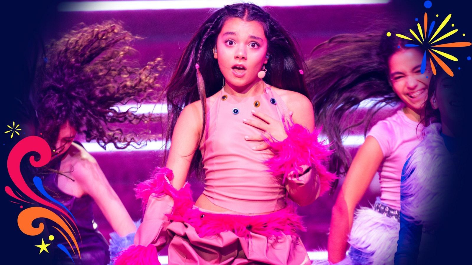 Joven cantante en un escenario con iluminación rosa y violácea, interpretando una canción junto a otras dos compañeras en una actuación musical.