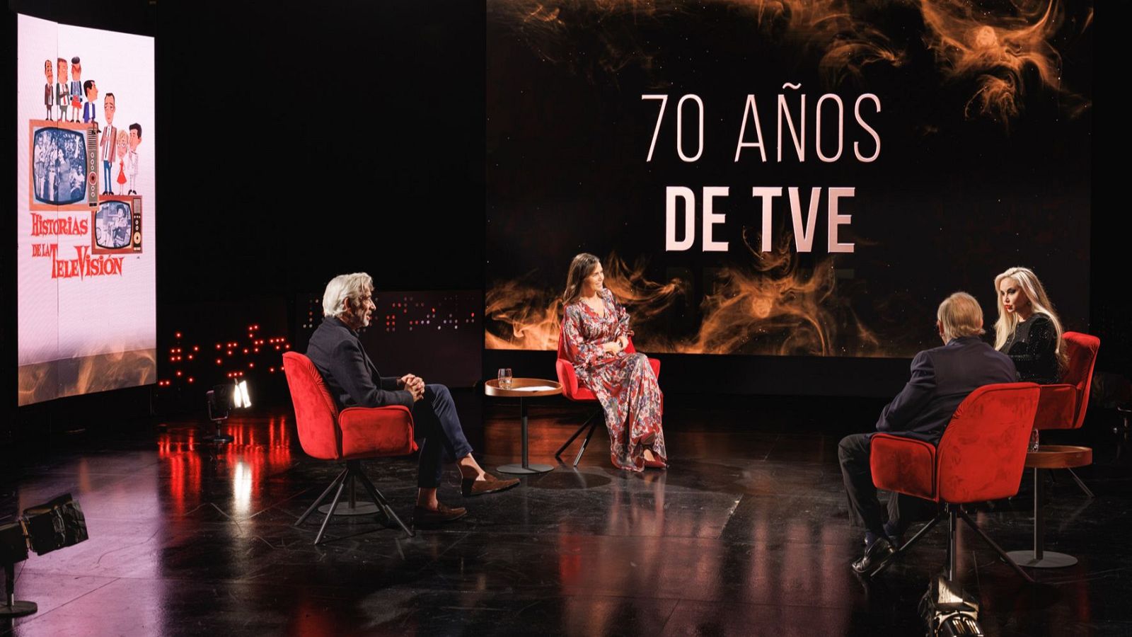 Plató de un programa de cine con cuatro personas conversando en sillones rojos, una pantalla con el texto 70 AÑOS DE TVE y suelo brillante.