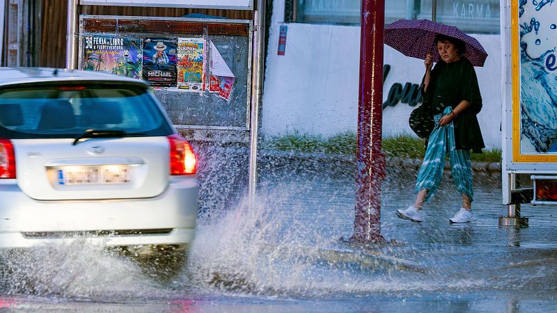 Una mujer se protege se protege de la lluvia con un paraguas.