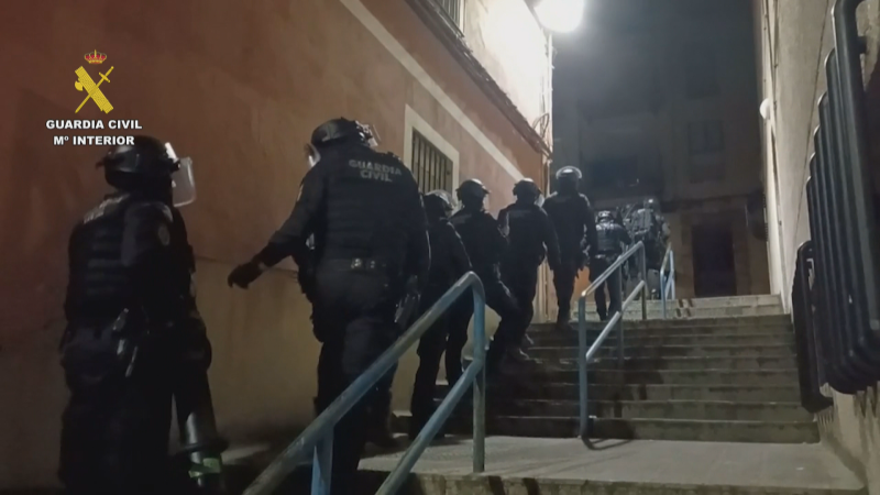 Agentes de la Guardia Civil con equipo táctico y cascos avanzan de noche por una escalinata urbana.