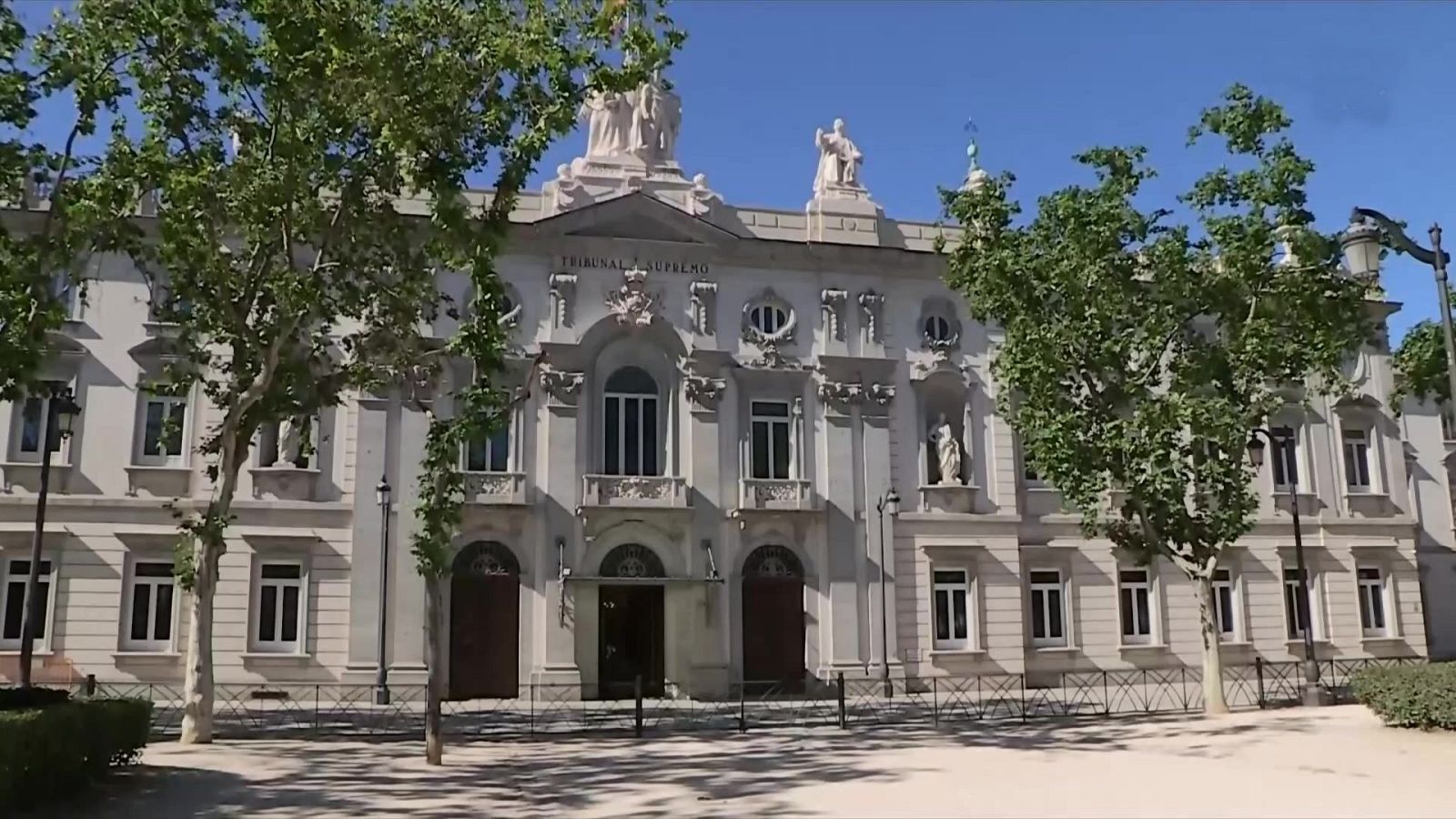 Fachada clasicista del edificio del Tribunal Supremo de España en Madrid, con la inscripción grabada, ventanales simétricos y una explanada arbolada en primer plano.