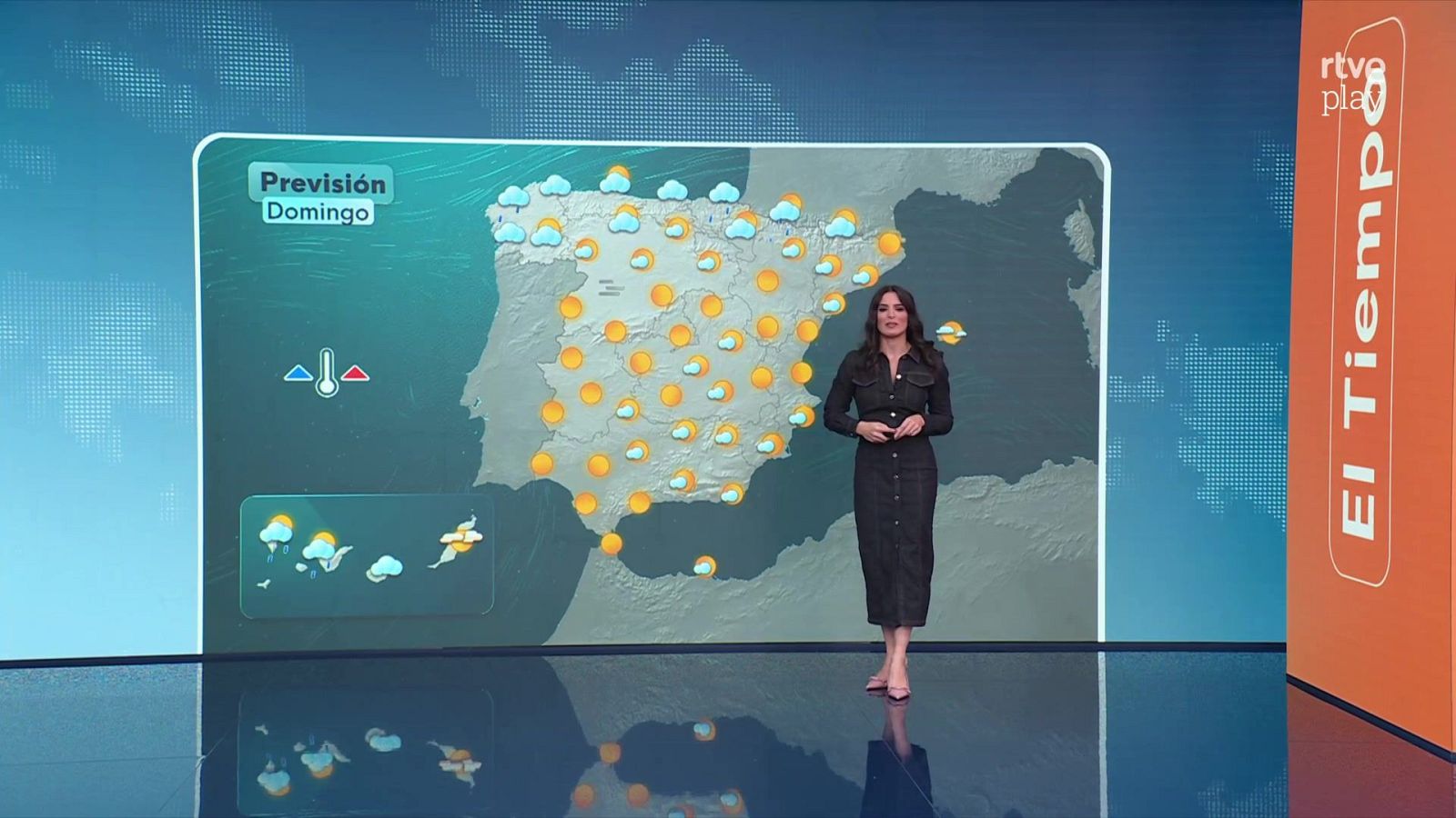 La presentadora Núria Seró presenta la previsión meteorológica de España en el plató de RTVE ante un gran mapa con iconos de sol y lluvia.