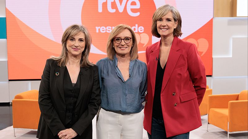 Tres mujeres sonrientes posan en el plat� de un programa de televisi�n frente a una pantalla con motivos anaranjados y el texto RTVE responde.