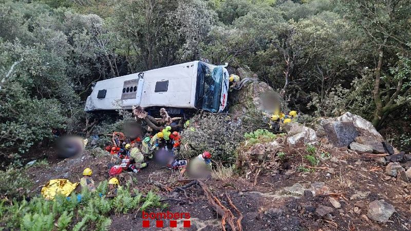 Autobús volcado en una ladera boscosa donde equipos de emergencia realizan labores de rescate. CONTEXTO: Grave accidente de autobús en Barcelona Fin de semana 24h
