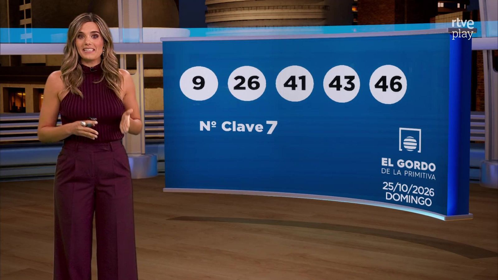 Presentadora en plató junto a un panel azul con los resultados del sorteo, esferas con números y logotipo de RTVE.