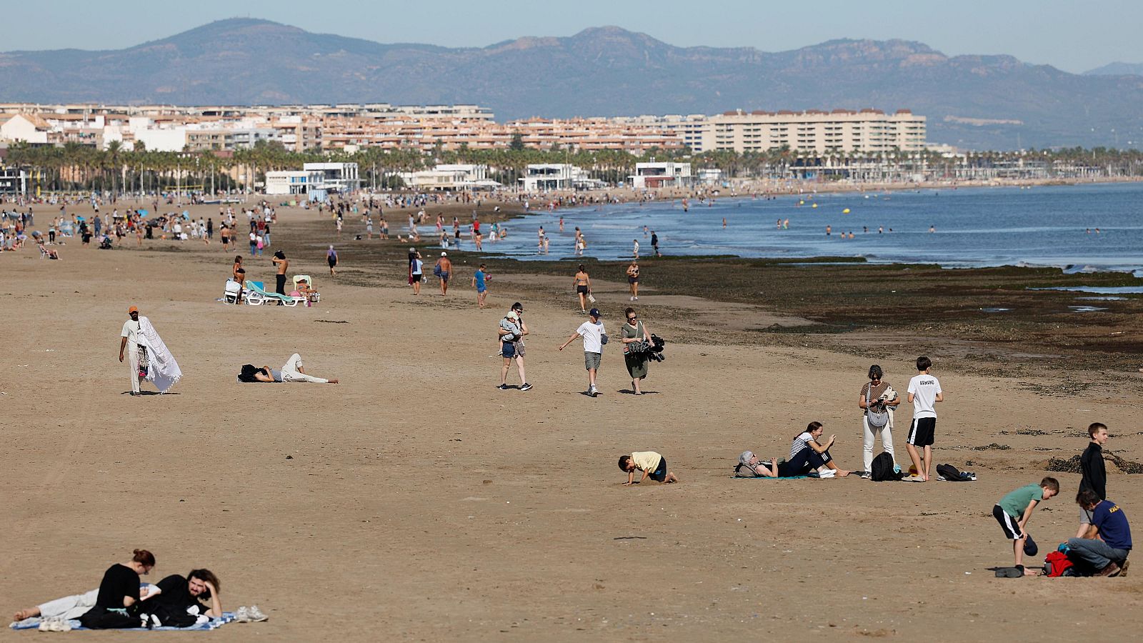Varias personas disfrutan en la playa de las Arenas, de las agradables temperaturas que se registran este domingo en Valencia