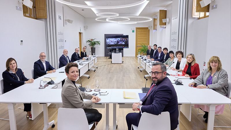 Reunión institucional con la presidenta de Navarra, María Chivite, y el ministro Ángel Víctor Torres en una sala moderna con mesas en U y pantallas al fondo.