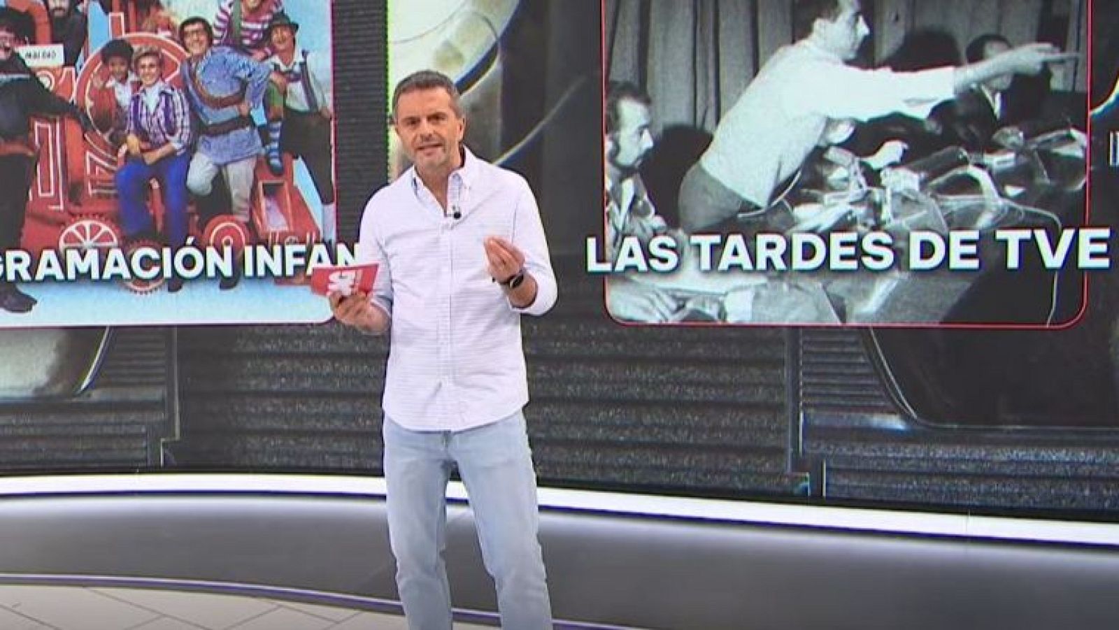 Presentador en plató con camisa blanca y vaqueros, frente a pantallas con imágenes de televisión infantil y técnica.