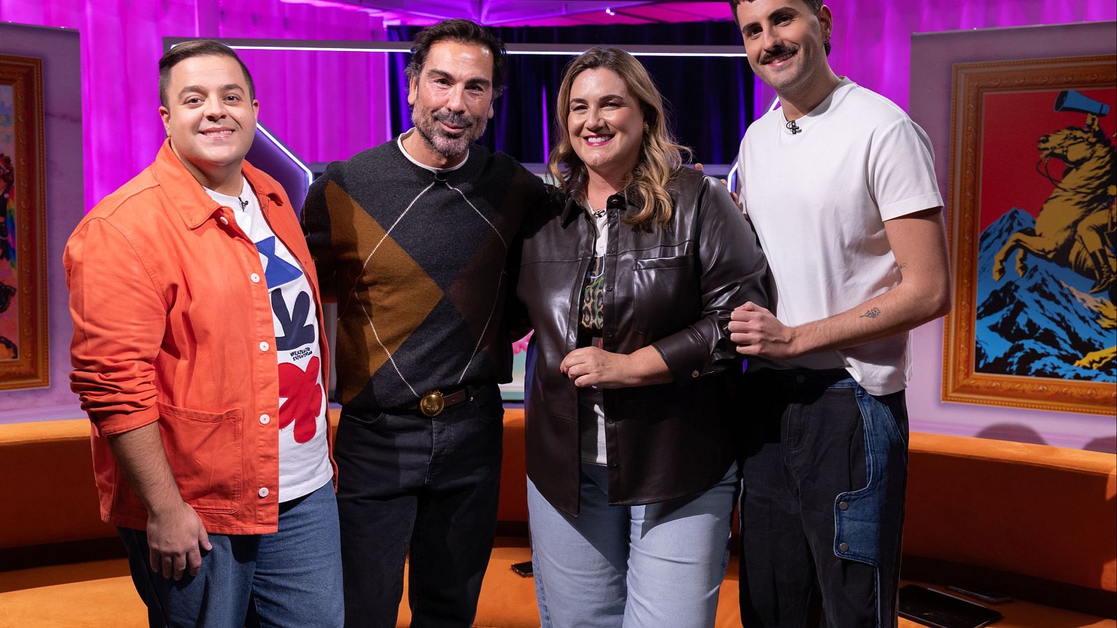 Cuatro conocidos rostros de la televisión española posan sonrientes en el plató de un videopódcast, iluminados con tonos magenta y violeta sobre un fondo de cortinajes oscuros.