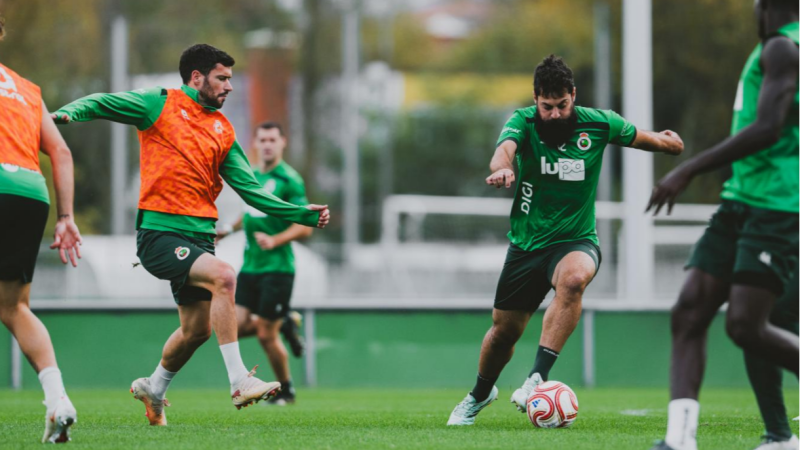 Entrenamiento de fútbol en un campo de césped con Unai Vencedor conduciendo el balón vistiendo equipación verdiblanca.
