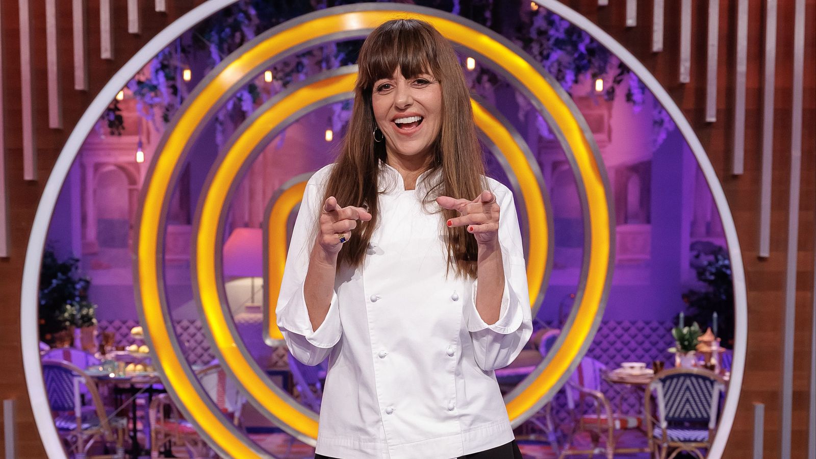 Yolanda Ramos posa alegremente con chaquetilla de chef blanca señalando a la cámara en el plató de MasterChef Celebrity.