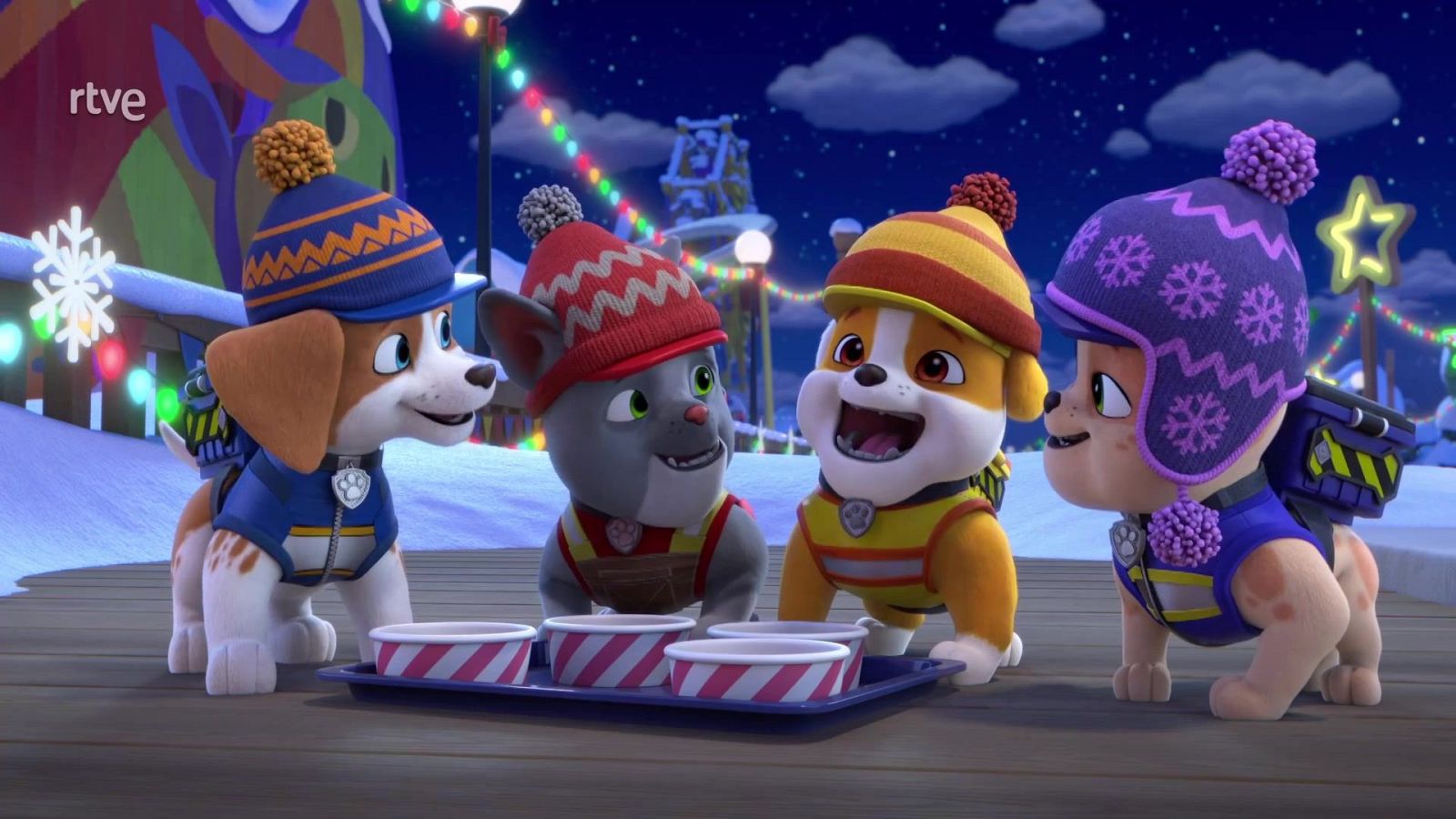 Cuatro cachorros animados con ropa de invierno y gorros de lana sonríen reunidos de noche en un entorno nevado y festivo iluminado con luces de colores.