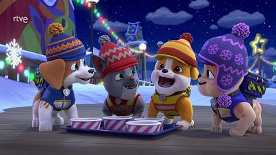 Cuatro cachorros animados con ropa de invierno y gorros de lana sonríen reunidos de noche en un entorno nevado y festivo iluminado con luces de colores.