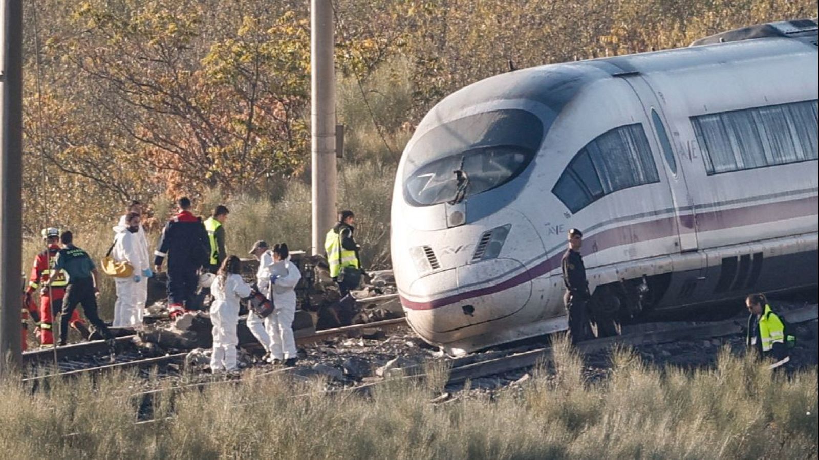 Accidente ferroviario de un tren de alta velocidad con daños en la cabina y un equipo de emergencias y peritos inspeccionando las vías.