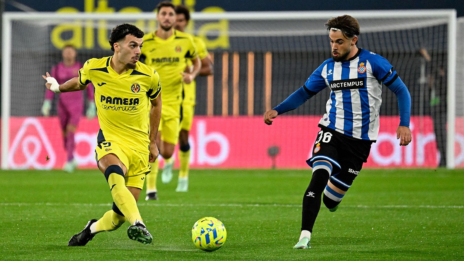 Álex Baena, del Villarreal CF, controla el balón ante la presión de Antoniu Roca, del RCD Espanyol, durante un partido de liga sobre el césped verde.