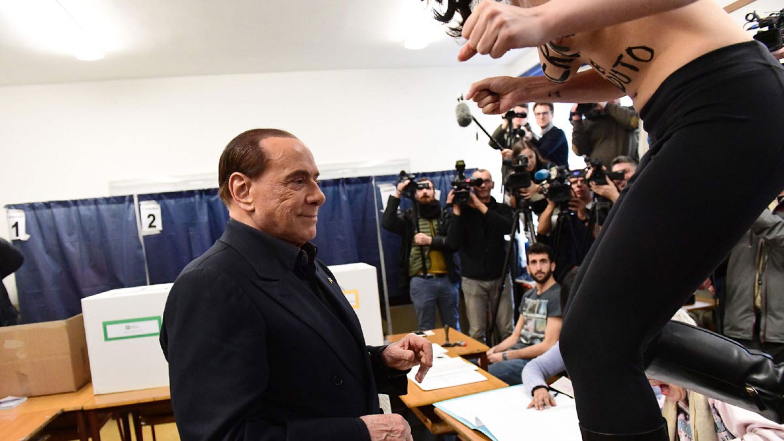 Una activista de Femen irrumpe durante la votación de Berlusconi con el torso desnudo