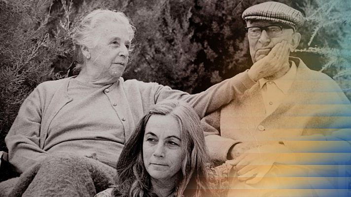 Una fotografía en blanco y negro muestra a tres personas sentadas en un entorno natural. Se distinguen dos mujeres, una mayor con cárdigan y otra más joven con cabello largo, y un hombre mayor con gorra y gafas.