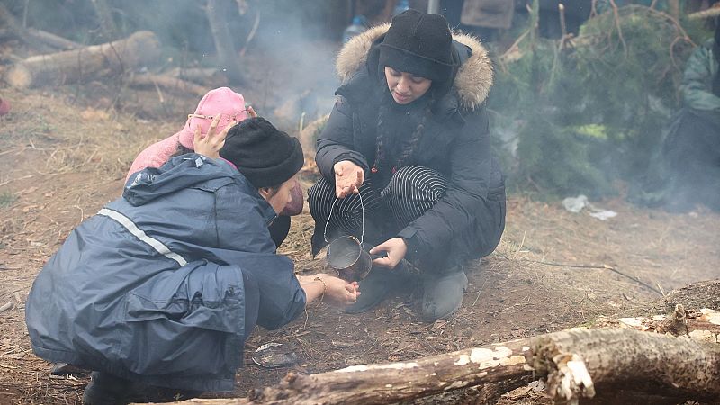 Tres mujeres agachadas se sirven agua de una lata