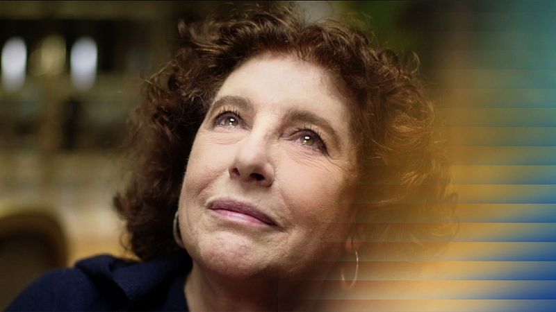 Retrato de primer plano de Charo López, actriz española de cabello rizado y mirada serena. Viste prenda azul y pendientes plateados.